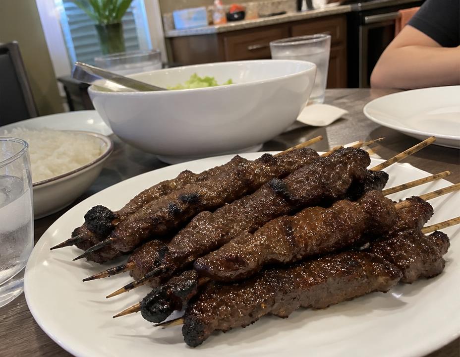 Espetinhos de carne em prato sobre a mesa da cozinha