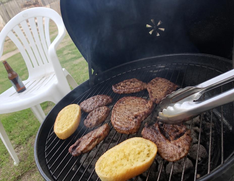 Carnes e pão de alho na churrasqueira no quintal de casa